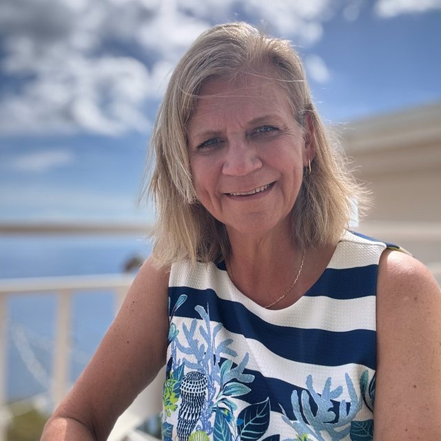 Kelly Fitzgerald, smiling, outdoors against a blue sky
